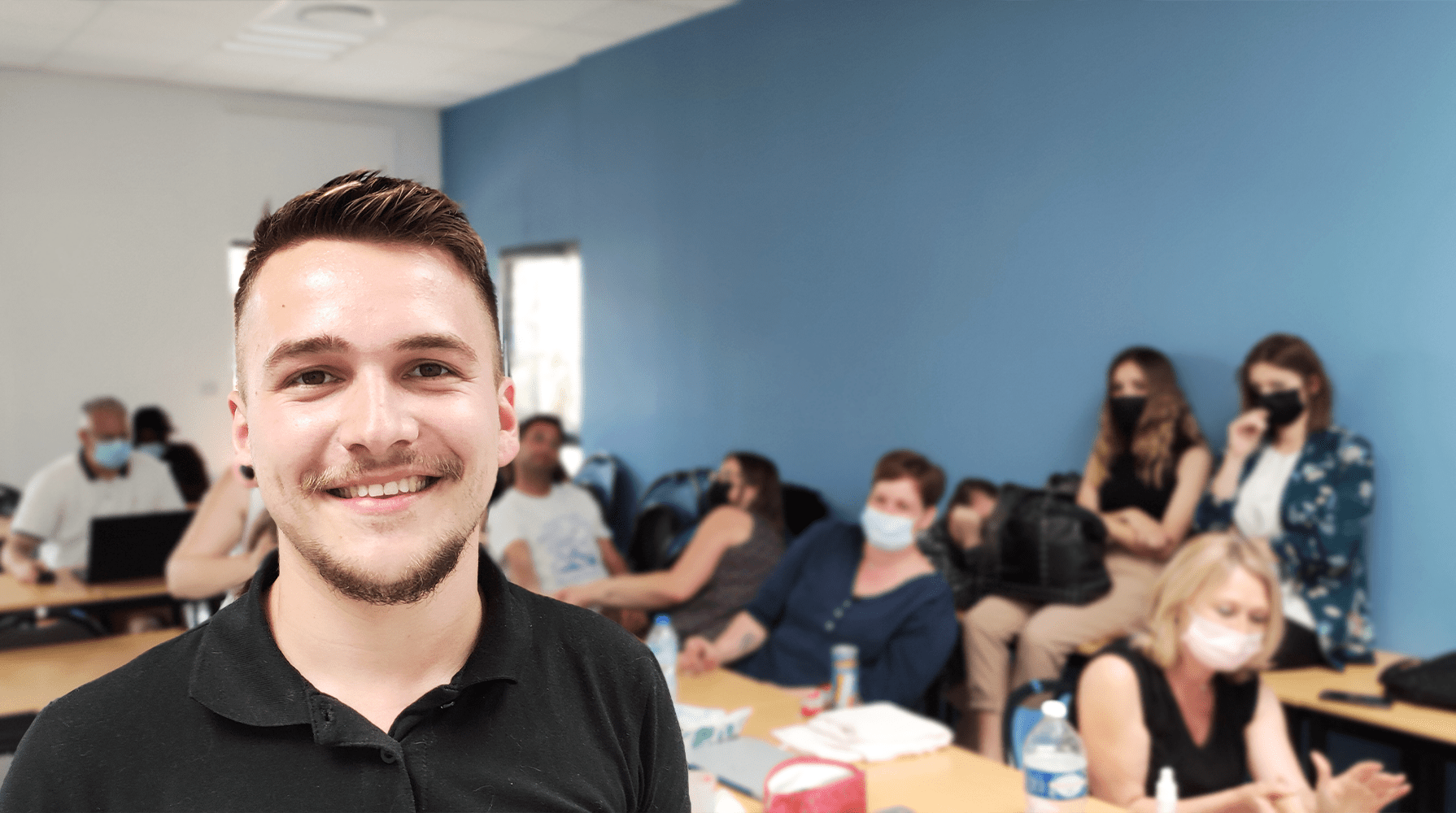 Homme souriant debout devant un groupe de personnes en cours