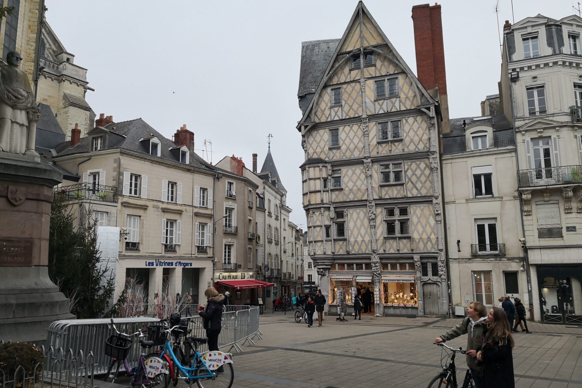 Place animée à Angers avec des cafés en terrasse, des passants et des bâtiments historiques autour