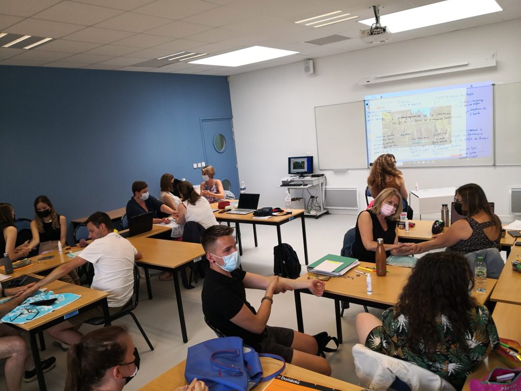 Salle de cours à l'IFAS d'Angers avec des étudiants attentifs, assis à leurs bureaux, écoutant un formateur devant un tableau blanc